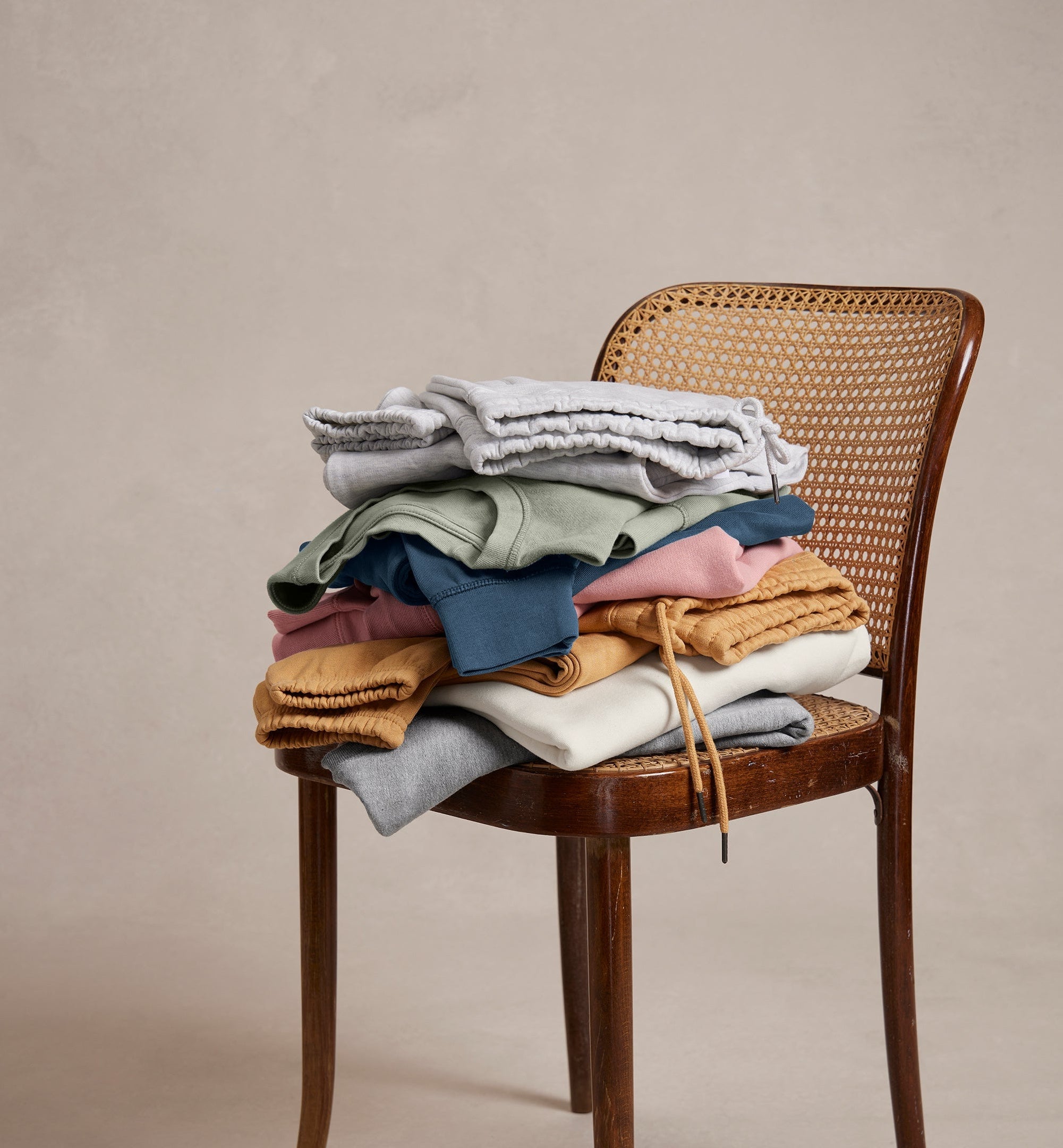 Stack of colorful clothes on a wooden chair against a beige background