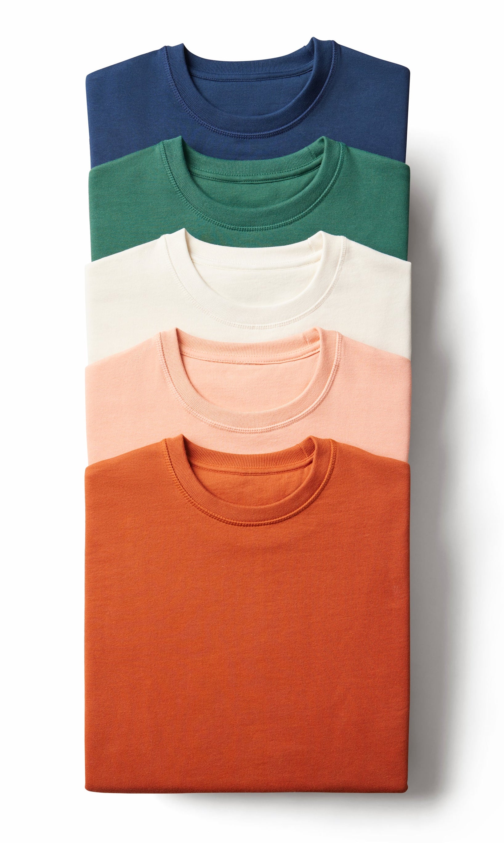 Stack of folded shirts in blue, green, white, pink, and orange on a white background