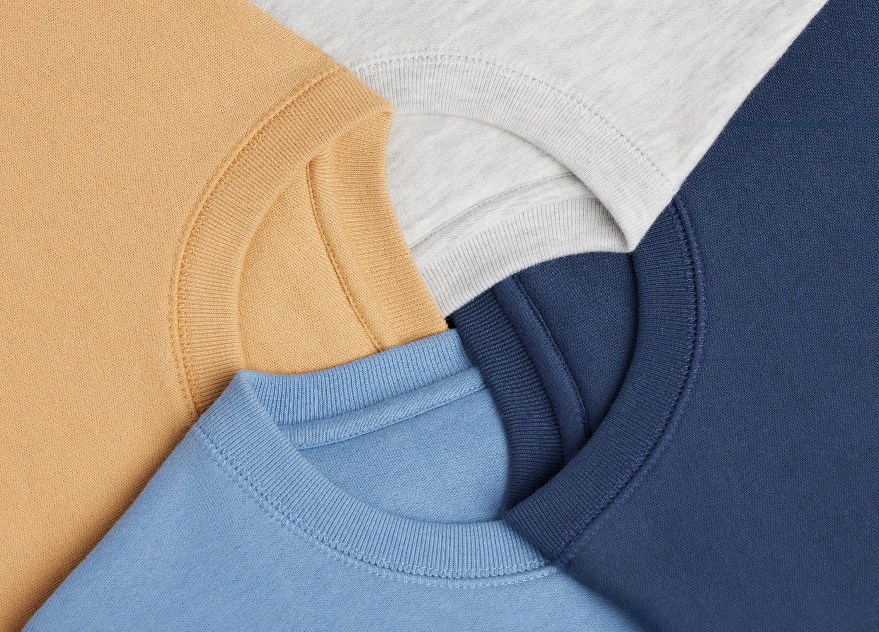 Close-up of four different colored sweatshirts: heather gray, navy, yellow, and cloudy blue.