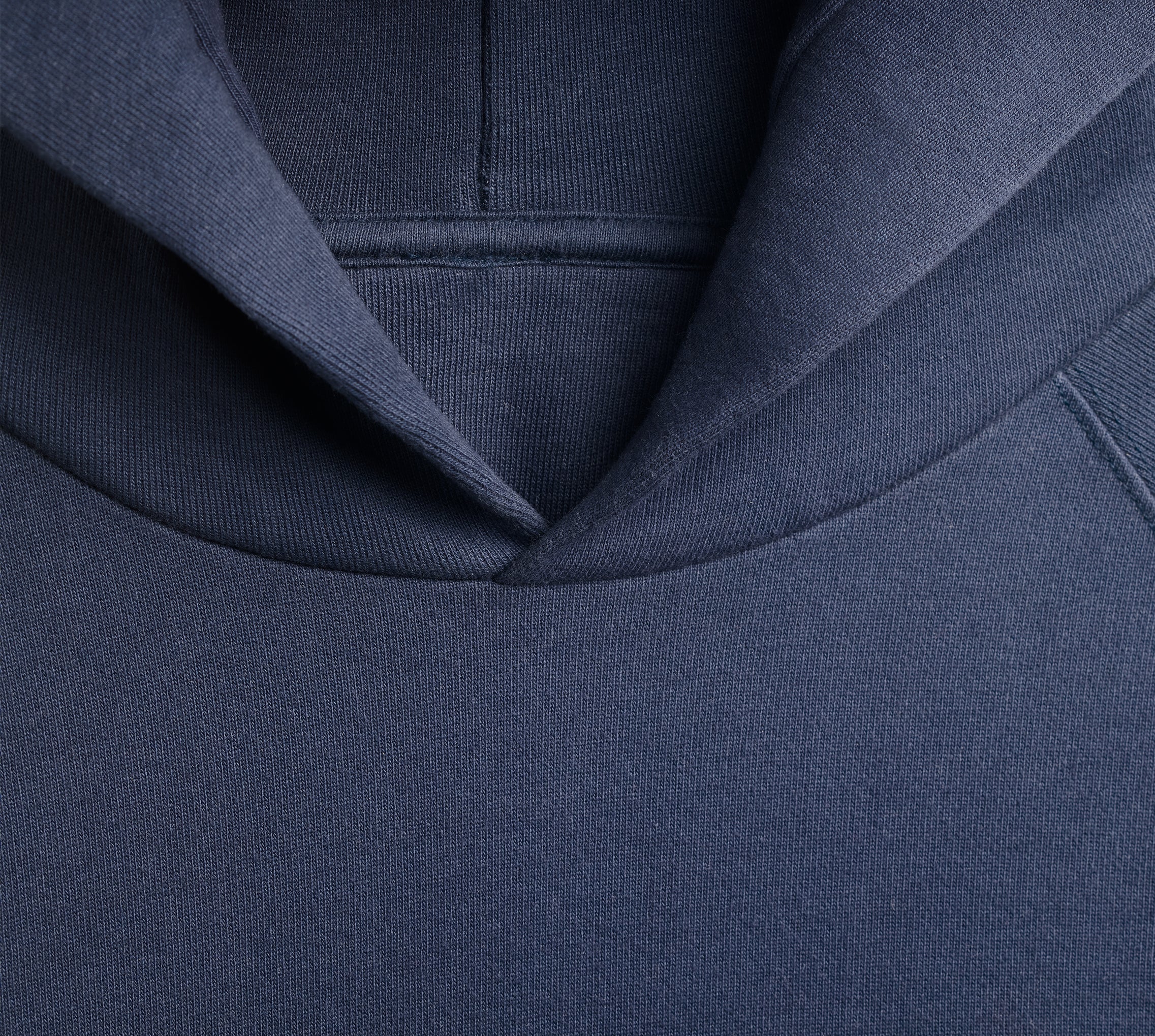 Close-up of a navy blue hoodie with a hood on a white background